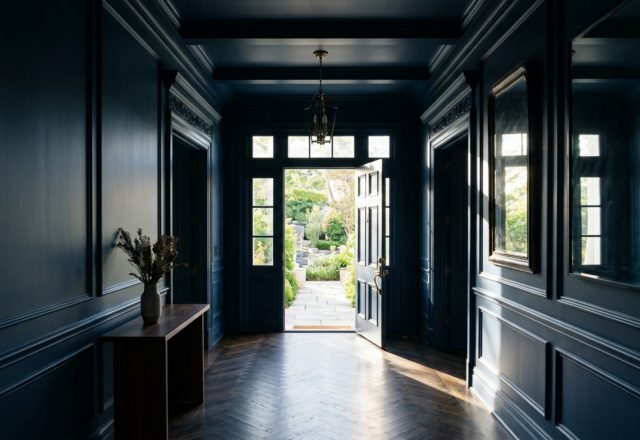 A grand foyer featuring Benjamin Moore Hale Navy color drenching on walls and ceiling with 36-inch clearance and natural side lighting.