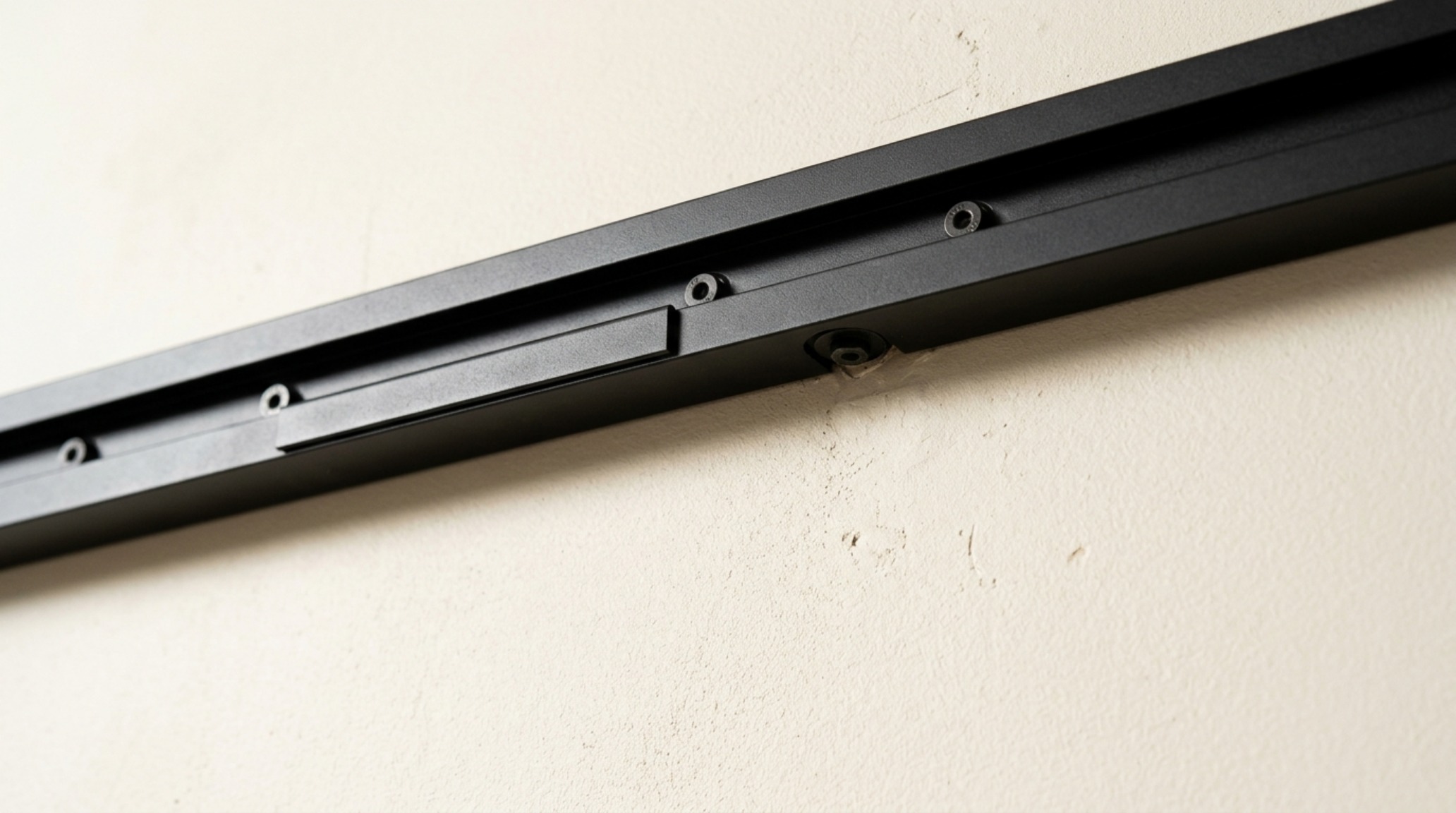 Close-up of matte black architectural hardware and vertical storage tracks against a Benjamin Moore Swiss Coffee painted shed interior wall.