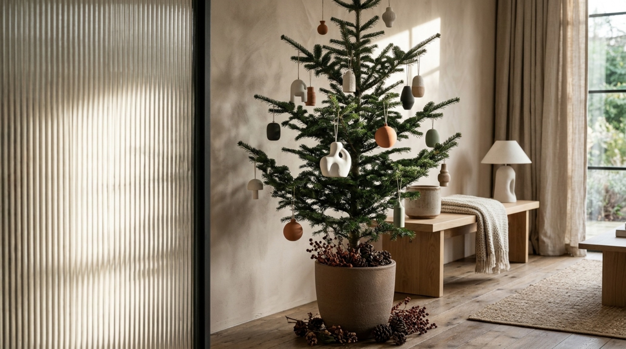 Modern designer xmas trees ideas featuring a deconstructed Alpine balsam with matte ceramic ornaments in a sunlit living room with Farrow & Ball Setting Plaster walls. Modern designer xmas trees ideas featuring a deconstructed Alpine balsam with matte ceramic ornaments in a sunlit living room with Farrow & Ball Setting Plaster walls.