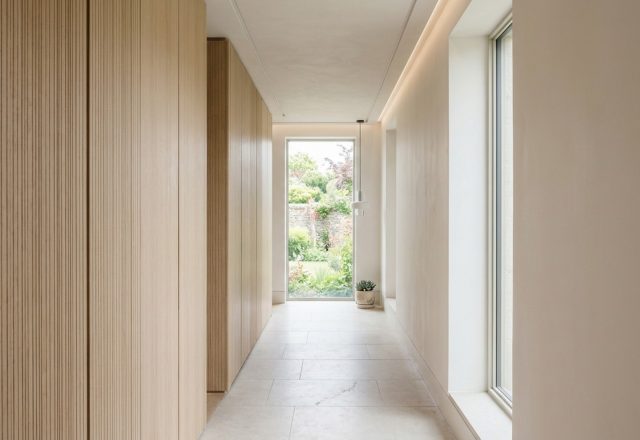 High-end minimalist hallway featuring custom fluted white oak hidden storage cabinets with a 36-inch clear walkway for optimal flow.