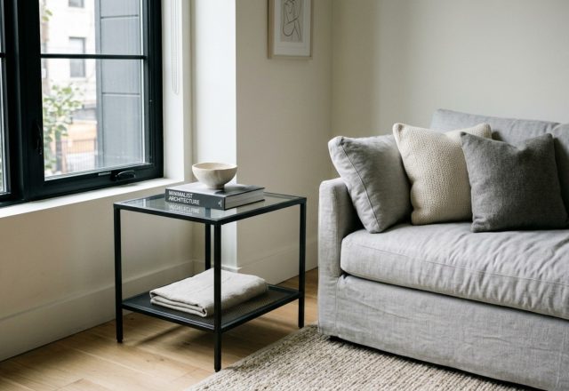 A minimalist living room featuring the ikea vittsjoe side table for small decor ideas styled with a brass task lamp and a single art book.