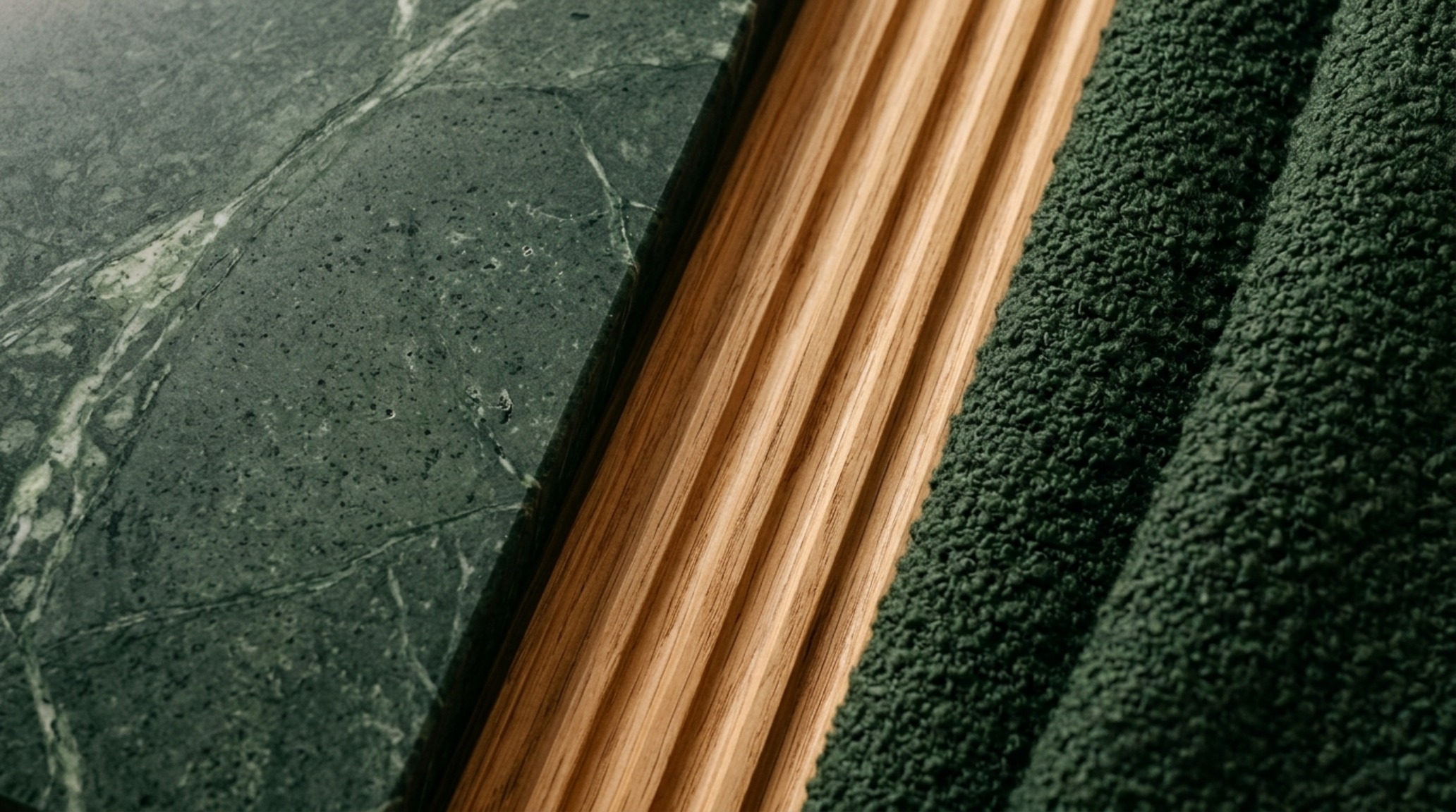 Close-up of luxury textures including a honed Verde Guatemala marble coffee table placed exactly 18 inches from a moss-colored mohair sofa.