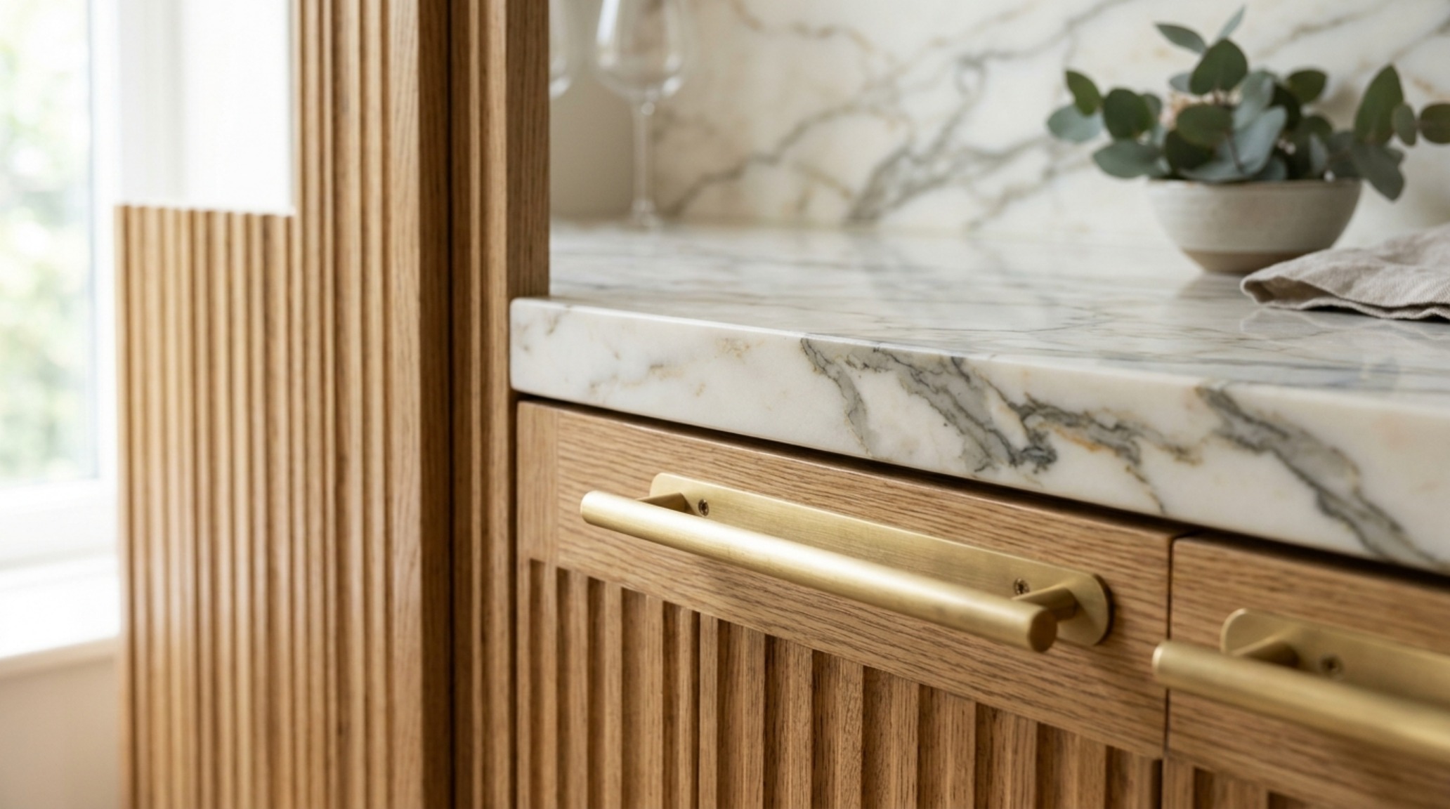 A close-up of luxury textures including brushed brass hardware and fluted white oak millwork in a modern Manhattan residence.