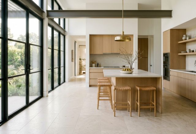 Large format kitchen tiles in a sun-drenched open plan kitchen featuring matte limestone-look porcelain and minimalist white oak cabinetry with 42-inch circulation paths.