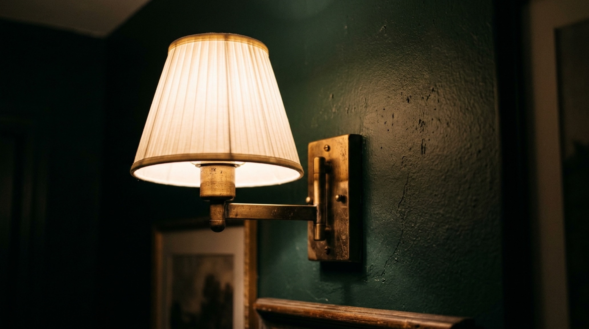 chic compact interior design with layered 2700K ambient lighting and brass sconces creating warmth in a moody apartment