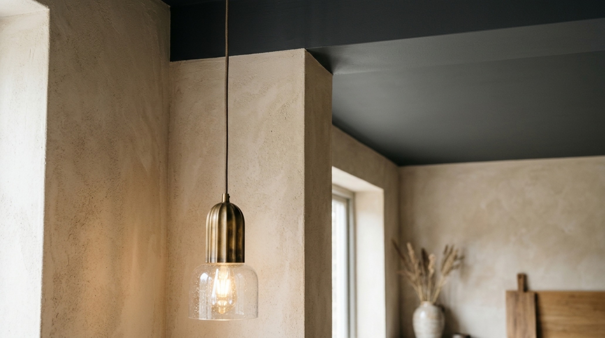 A residential interior detail showing the intersection of a limewash wall and brushed bronze hardware in an organic modern home.