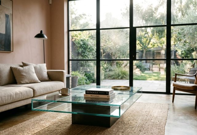 A minimalist living room featuring a floating architectural glass coffee table with 12mm polished edges, highlighting unbroken sightlines and visual weightlessness.