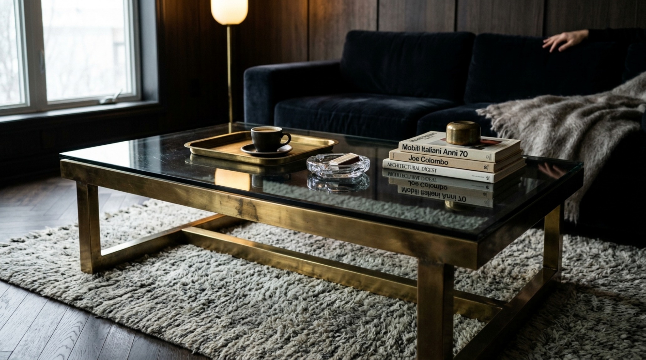 Luxury coffee table aesthetics featuring a dual-tier smoked glass design with brushed brass accents in a moody, sophisticated lounge setting. Luxury coffee table aesthetics featuring a dual-tier smoked glass design with brushed brass accents in a moody, sophisticated lounge setting.