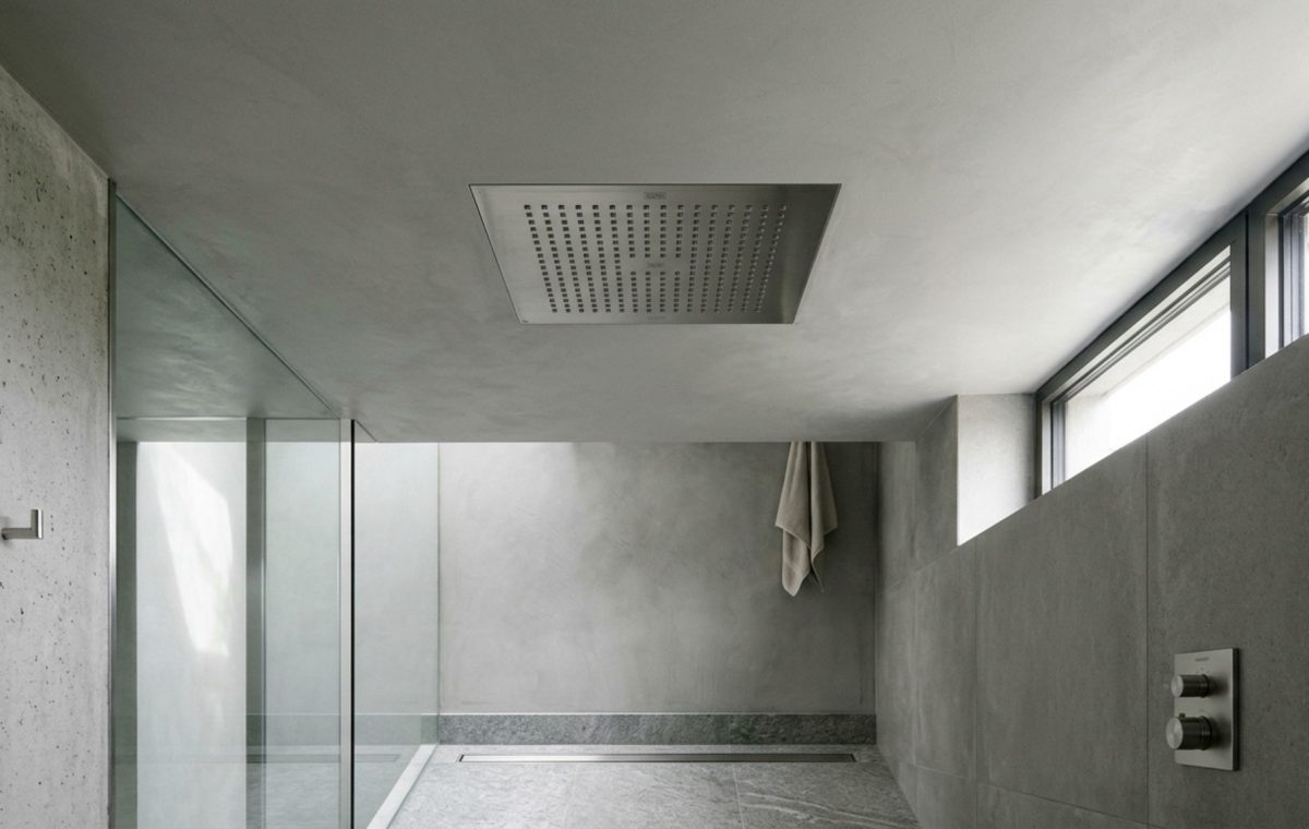 flush ceiling shower head installation seamlessly integrated into a soft-grey Tadelakt plaster ceiling with perimeter LED cove lighting.