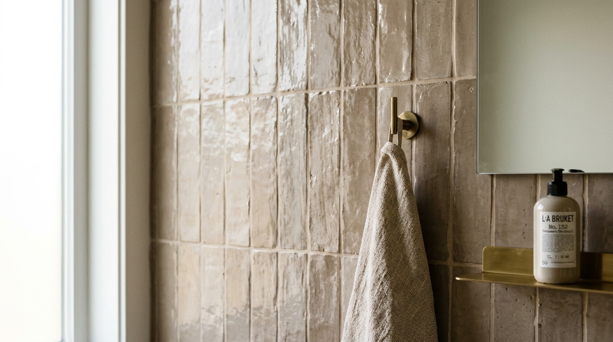Bathroom tile ideas for small bathrooms showcasing vertical zellige clay tiles in a warm taupe glaze with soft directional lighting. Bathroom tile ideas for small bathrooms showcasing vertical zellige clay tiles in a warm taupe glaze with soft directional lighting.