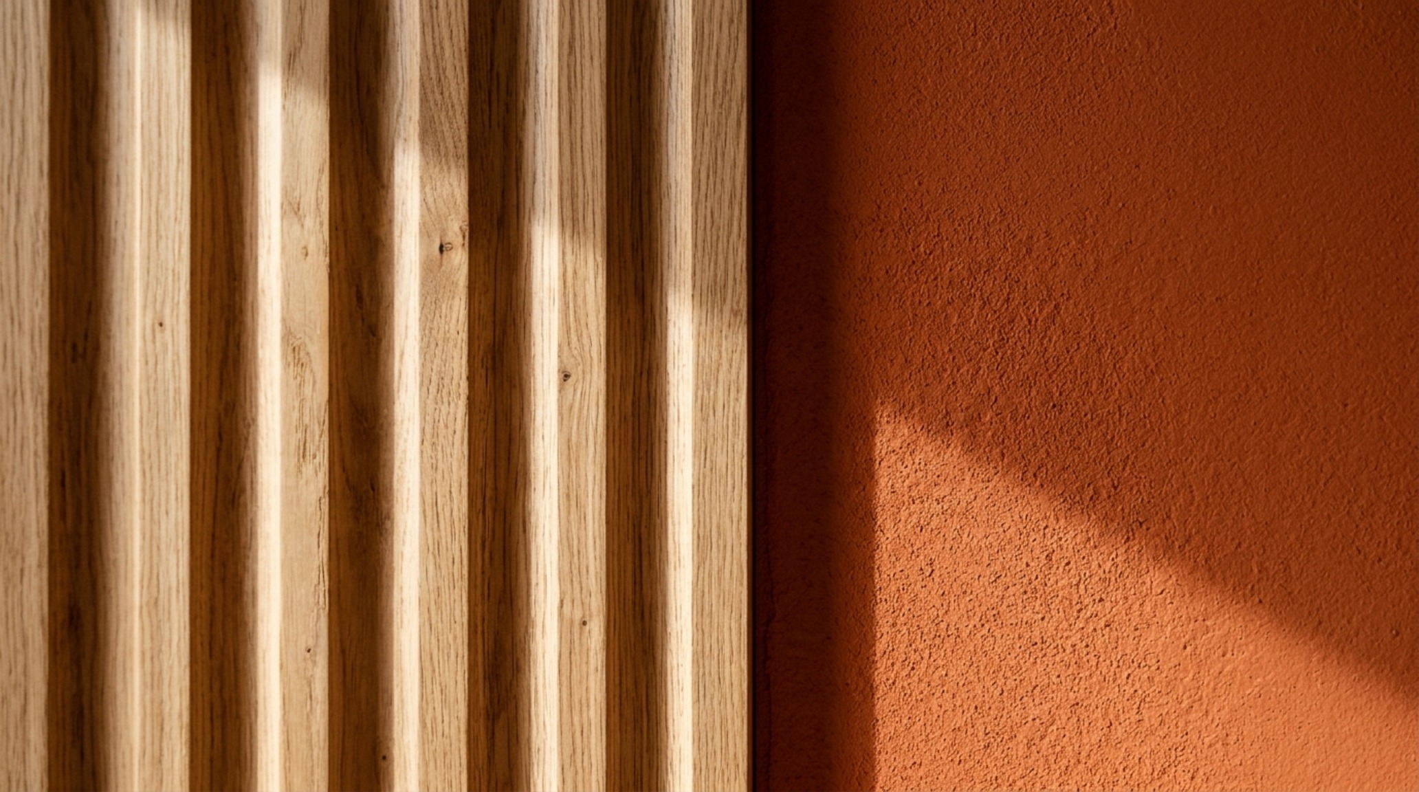 Close-up of a fluted white oak cabinet against a matte burnt orange wall, showcasing tactile materiality and shadow play in a luxury interior.