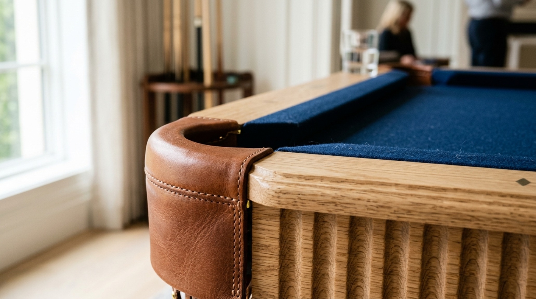 luxury pool dining tables textures showing a close-up of fluted oak legs and a leather-wrapped pocket detail