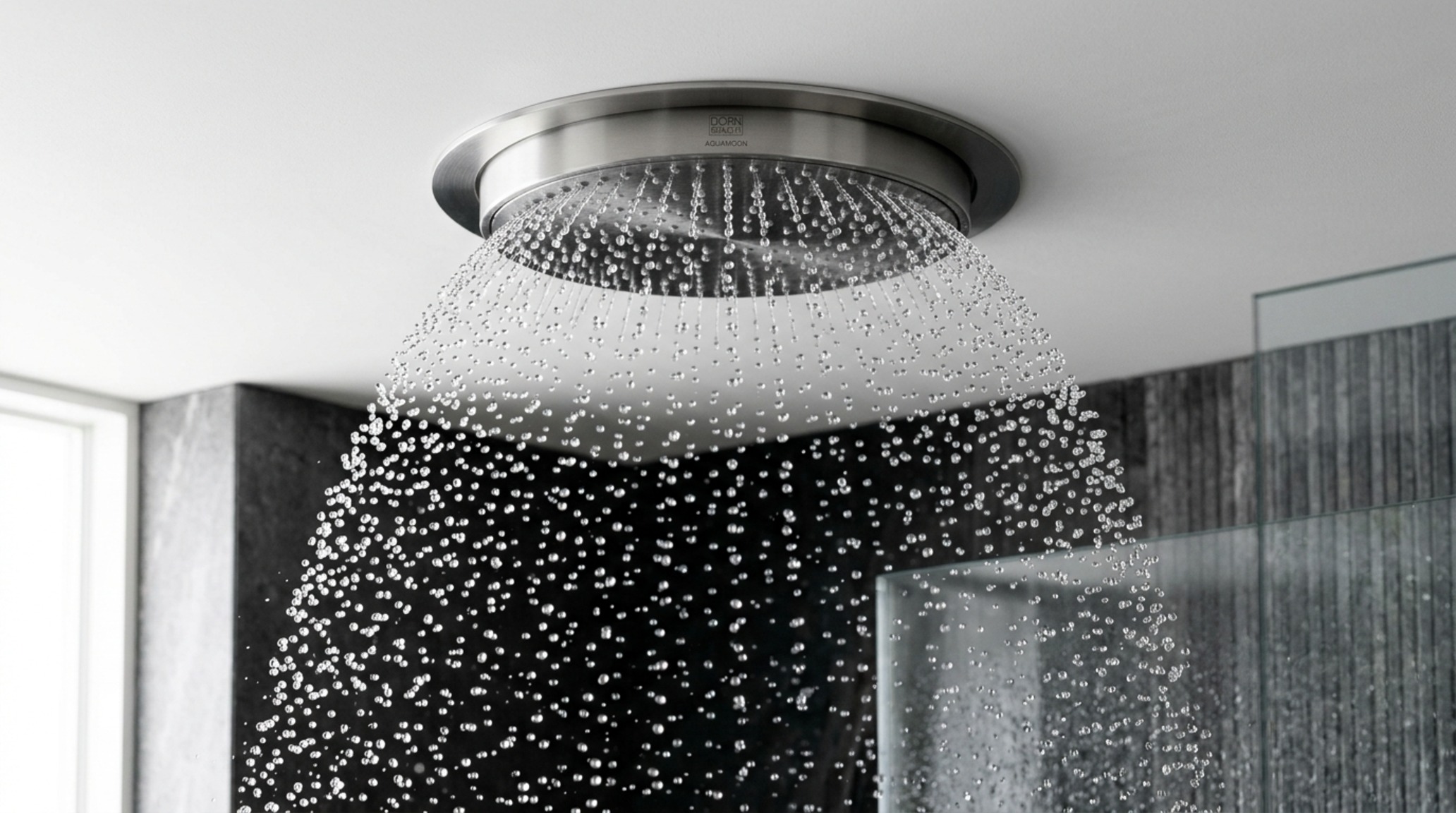 Dornbracht Aquamoon flow rates demonstrated through a concentrated dome of water falling into a minimalist wet room with basalt flooring.