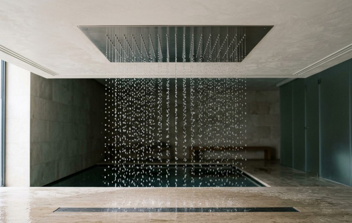 ceiling mounted rain panel recessed into a limestone ceiling with a precision spray pattern and integrated 2700K lighting.