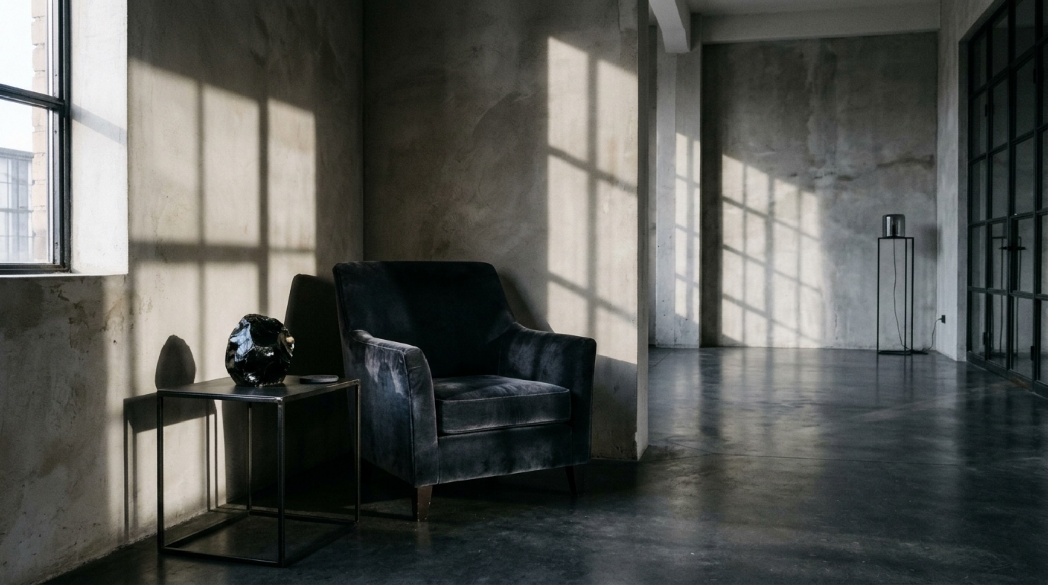 chic halloween living room ideas featuring a velvet charcoal sofa and a single oversized obsidian bowl on a modernist side table