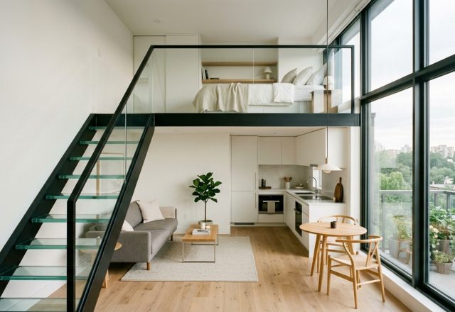 space-saving studio layout featuring a structural mezzanine sleeping loft with glass railings and light oak flooring in a high-ceiling urban apartment.