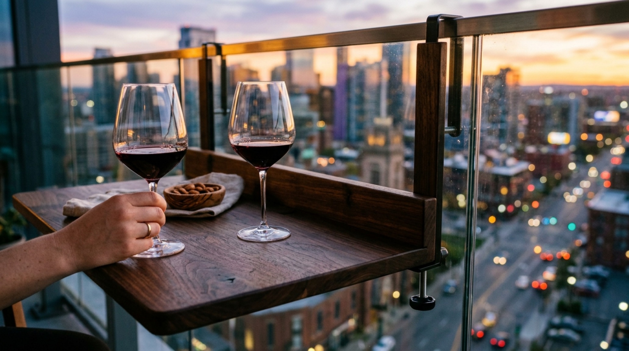 Luxury folding balcony bar table in dark walnut attached to a glass railing overlooking a city skyline. Luxury folding balcony bar table in dark walnut attached to a glass railing overlooking a city skyline.