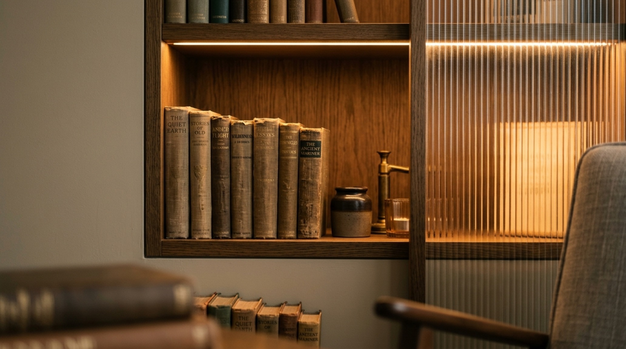 Close-up of internal LED shelf lighting with a 2700K warm glow, showcasing how light diffuses through fluted glass dividers to illuminate leather-bound books.
