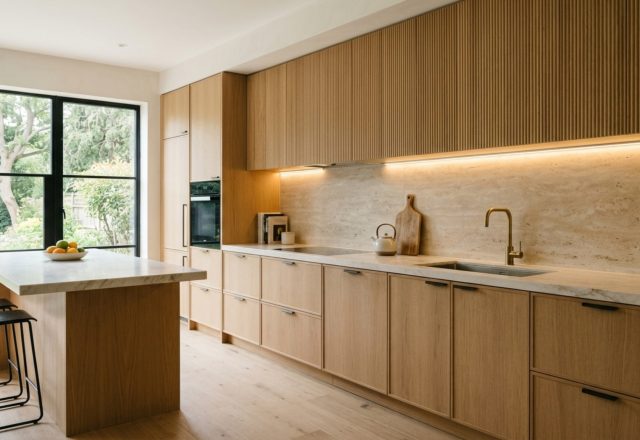 A wide-angle architectural shot of a minimalist kitchen with fluted white oak cabinets and soft 2700K ambient lighting, illustrating how to install hang cabinets decor ideas.