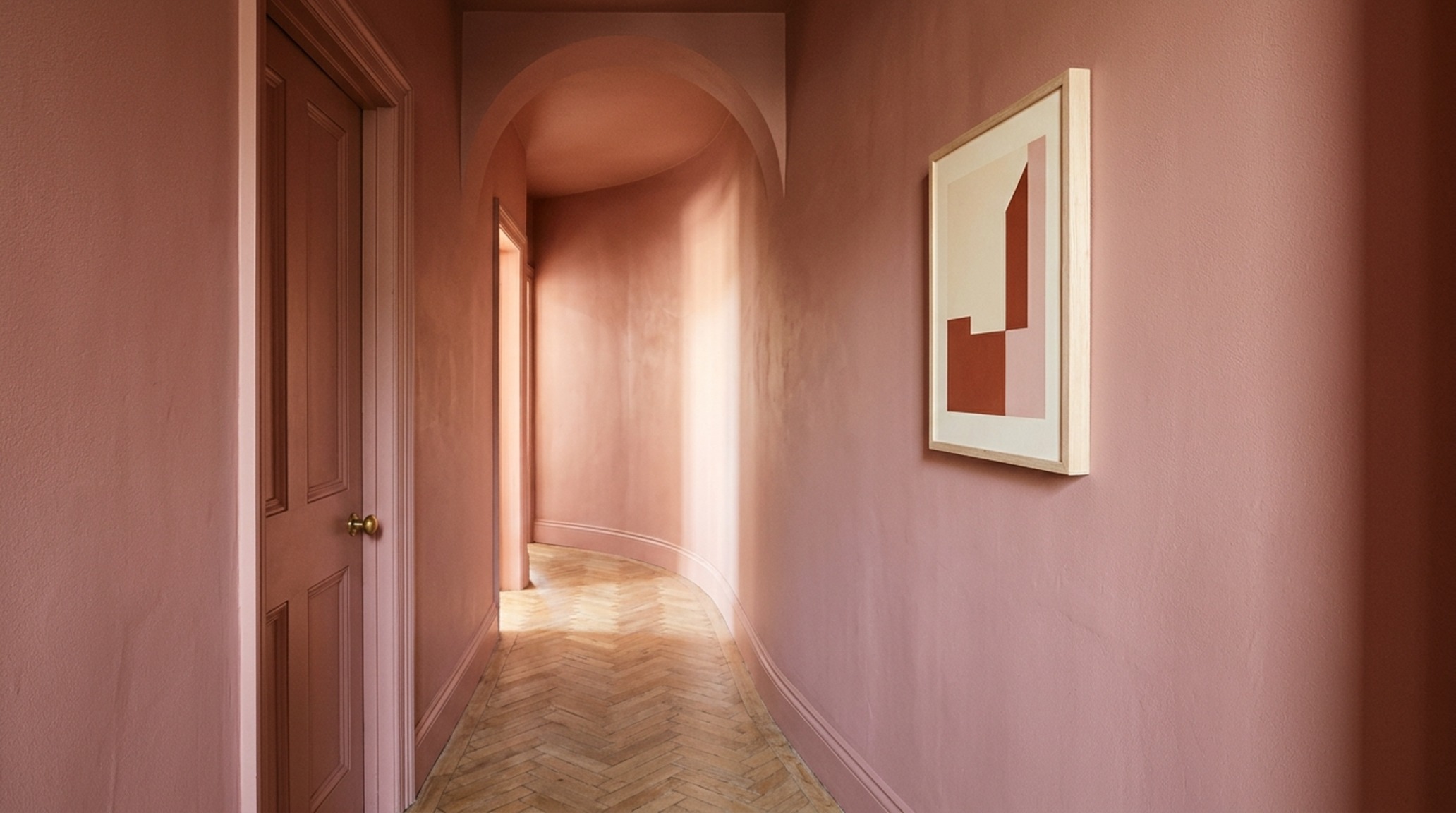 color drenching techniques in a hallway using a soft terracotta hue on walls and trim to elongate the visual sightlines