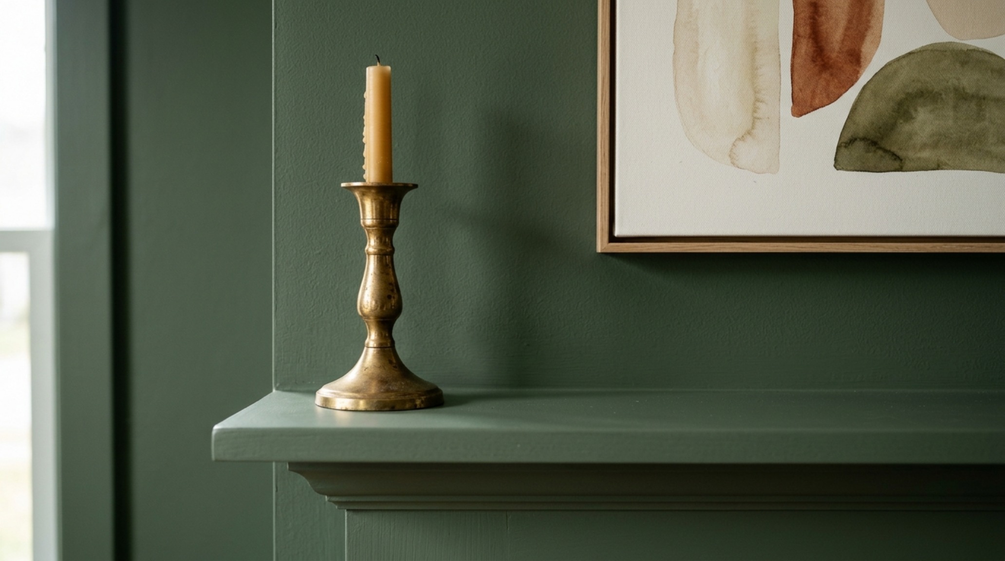 Detail of a Sherwin Williams Evergreen Fog living room wall featuring matte black hardware and a minimalist sage green accent wall decor arrangement.