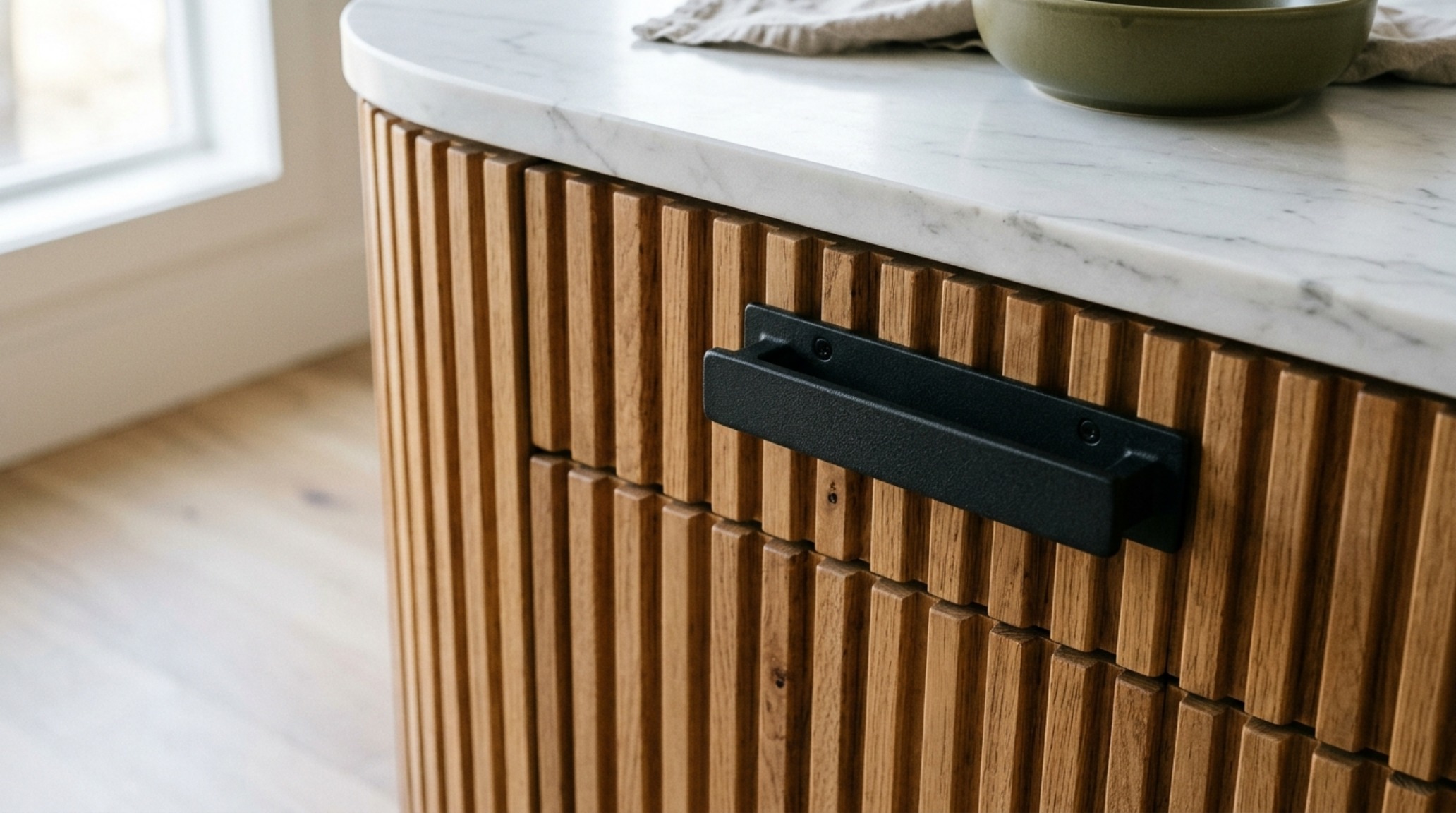 Matte black cabinet hardware details on fluted wood panels, illustrating the tactile dialogue between organic textures and industrial finishes. Matte black cabinet hardware details on fluted wood panels, illustrating the tactile dialogue between organic textures and industrial finishes.