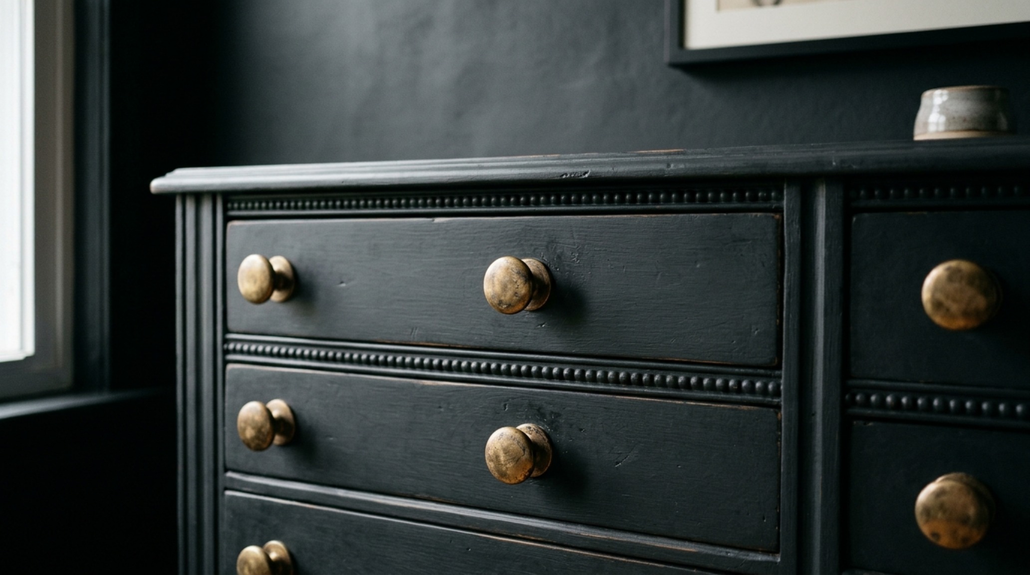 Close-up of unlacquered brass hardware on a monochromatic dresser, showcasing how tactile materials anchor upcycled furniture ideas for small spaces.