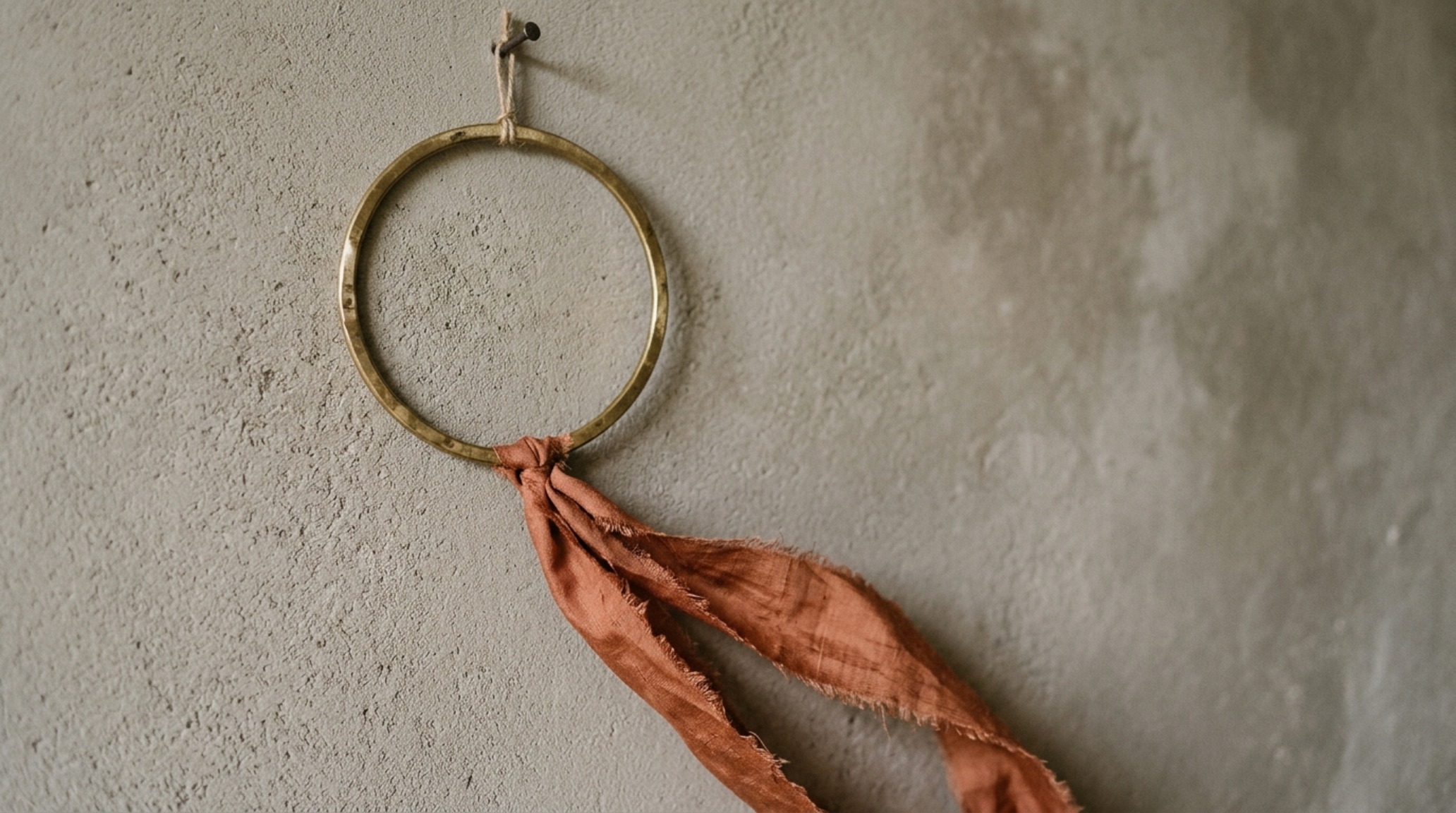 DIY minimalist wreath ribbon techniques showing a long vertical drop of terracotta velvet on a slim brass hoop. DIY minimalist wreath ribbon techniques showing a long vertical drop of terracotta velvet on a slim brass hoop.