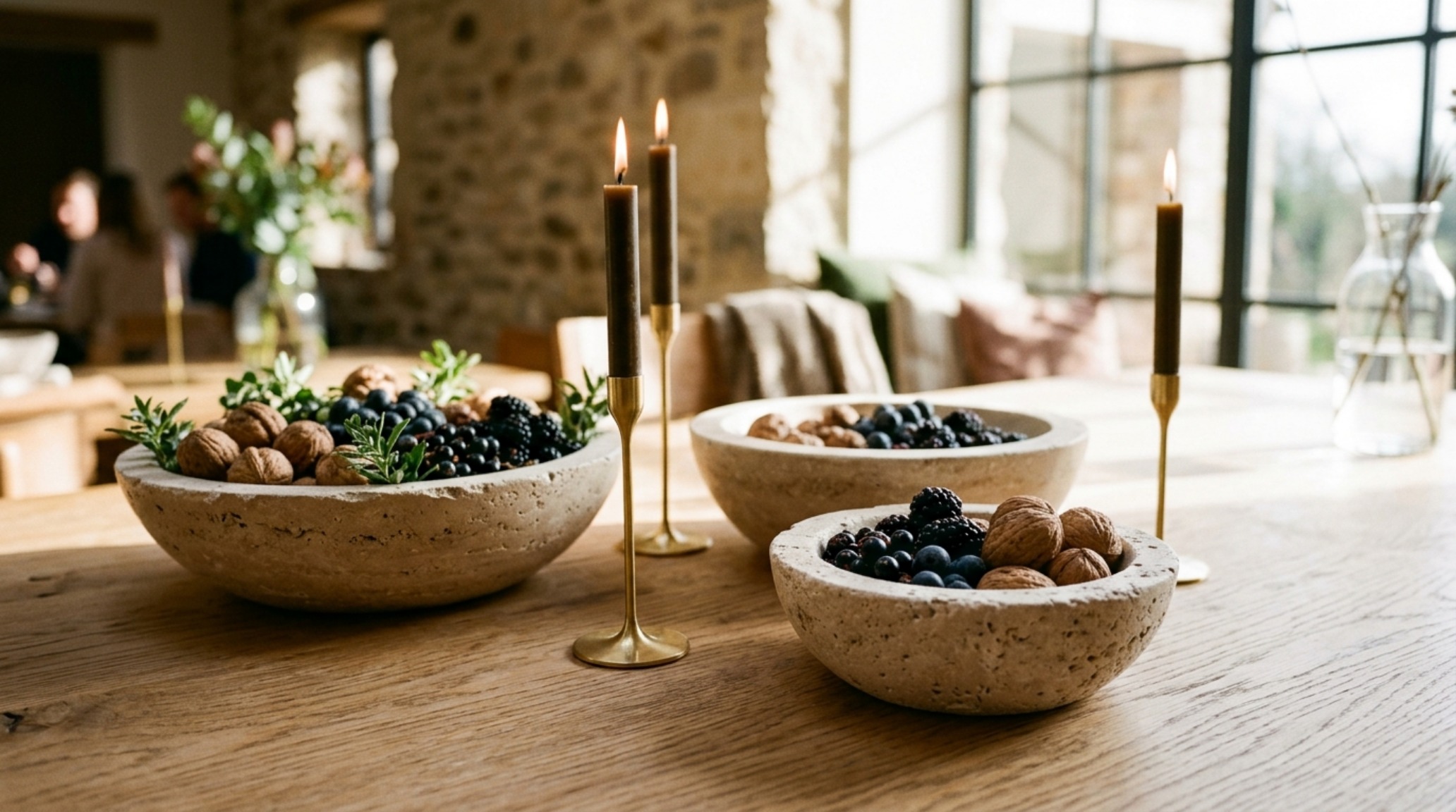 low-profile festive centerpieces featuring hand-carved travertine bowls and slim brass candle holders on a white oak table low-profile festive centerpieces featuring hand-carved travertine bowls and slim brass candle holders on a white oak table