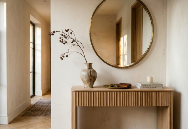 Editorial view of a narrow foyer featuring a custom slim-line console in white oak, topped with sculptural ceramics and atmospheric 2700K lighting.