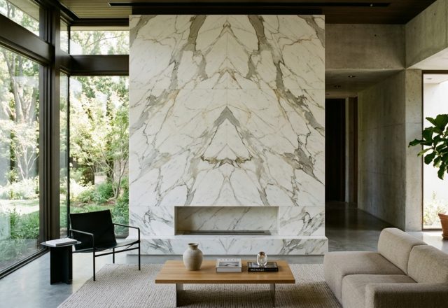 A floor-to-ceiling book-matched Calacatta marble fireplace in a modern living room, emphasizing the Golden Ratio and structural symmetry with adjacent floor-to-ceiling windows.