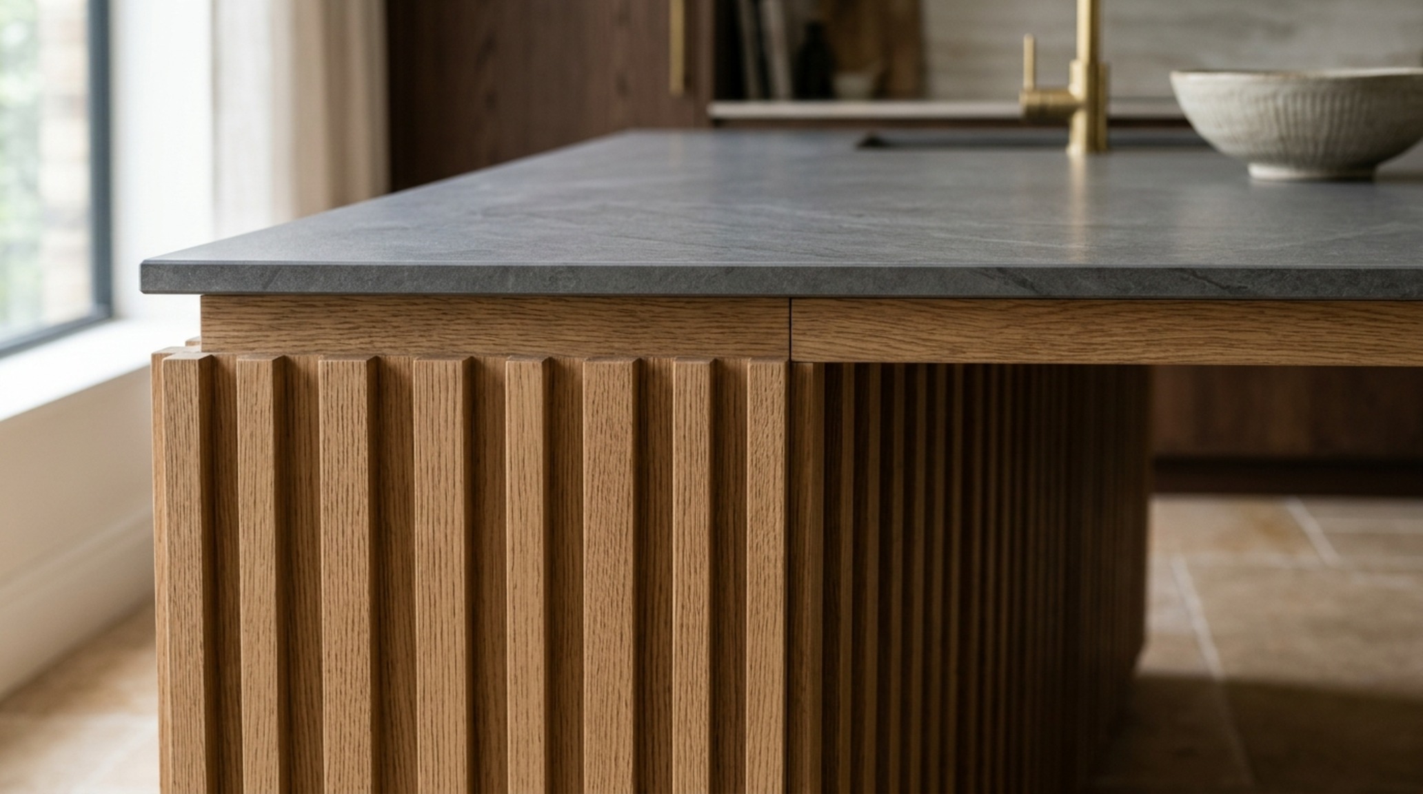 rift-cut oak kitchen finishes applied to a fluted island base with a honed stone countertop and warm LED lighting.