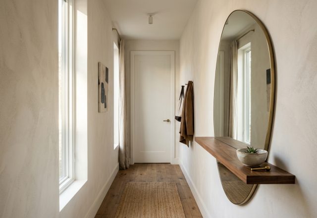 Hero shot of an organic shaped wall mirror with integrated walnut shelving in a narrow entryway, styled with minimalist ceramics and natural light.