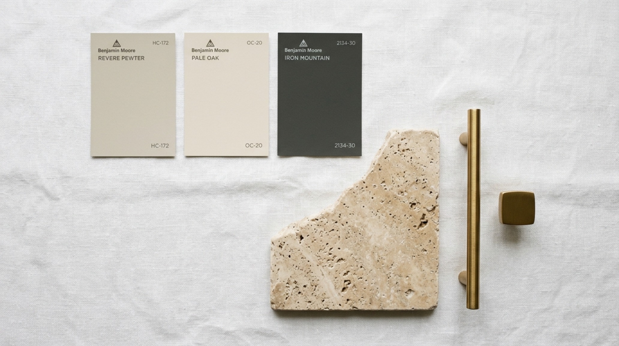 Close-up of designer paint swatches including Revere Pewter and Setting Plaster under 2700K warm ambient lighting conditions. Close-up of designer paint swatches including Revere Pewter and Setting Plaster under 2700K warm ambient lighting conditions.