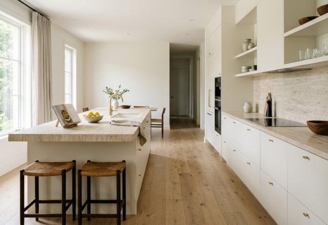 Modern kitchen featuring taupe cabinetry finished in waterborne alkyd enamel for durability, paired with honed travertine countertops and 36-inch walkway clearances.