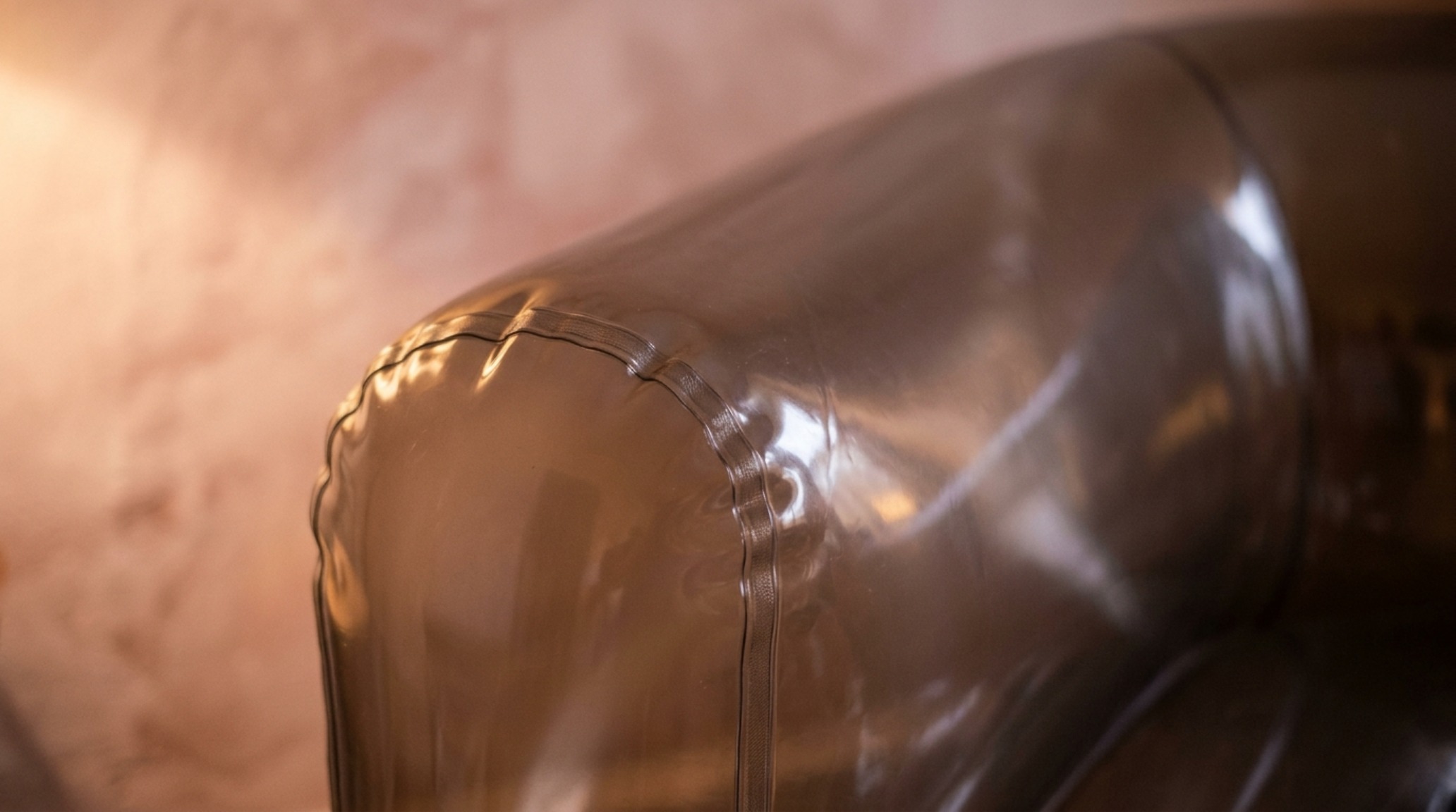 Close-up of a high-sheen inflatable chair surface softened by 2700K amber lighting and natural shadows from a nearby plant.