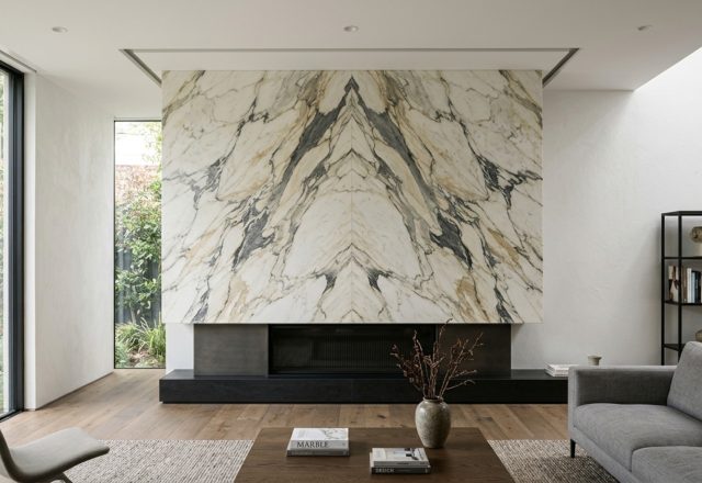 Contemporary marble fireplace ideas featuring a floor-to-ceiling slab of Calacatta marble with bookmatched veining and a recessed shadow gap at the ceiling.