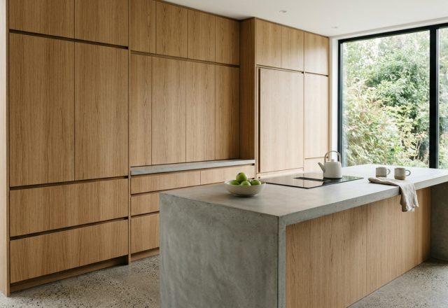 Minimalist handleless cabinetry in a modern style kitchen featuring vertical grain white oak and integrated shadow-gap finger pulls.