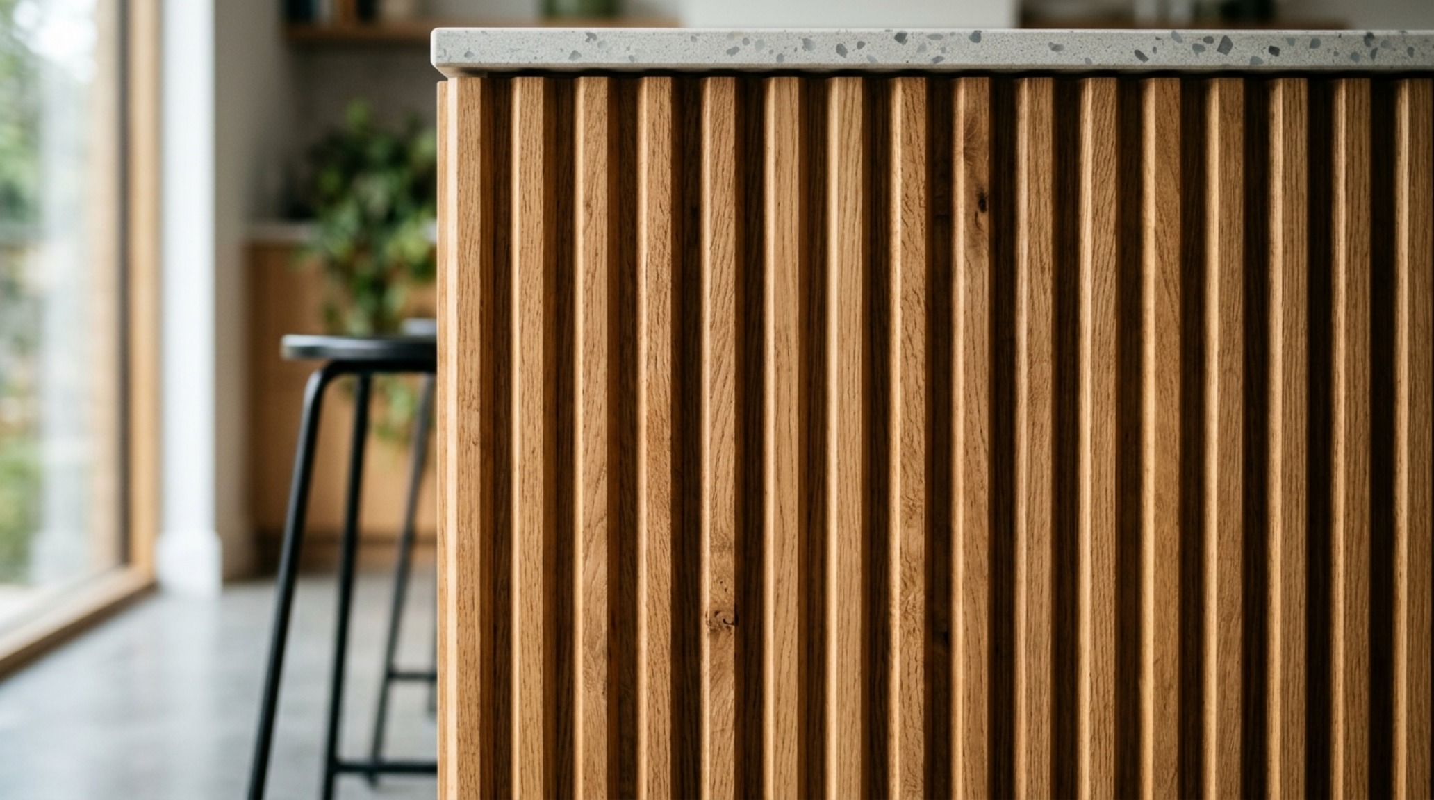 Detail of fluted white oak island base with integrated subtle warm LED toe-kick lighting at 2700K.