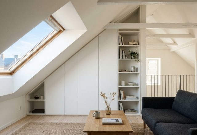 A bright Scandinavian loft attic conversion showcasing custom floor-to-ceiling invisible storage integrated into sloped ceilings, finished in Benjamin Moore Swiss Coffee for a seamless architectural look.