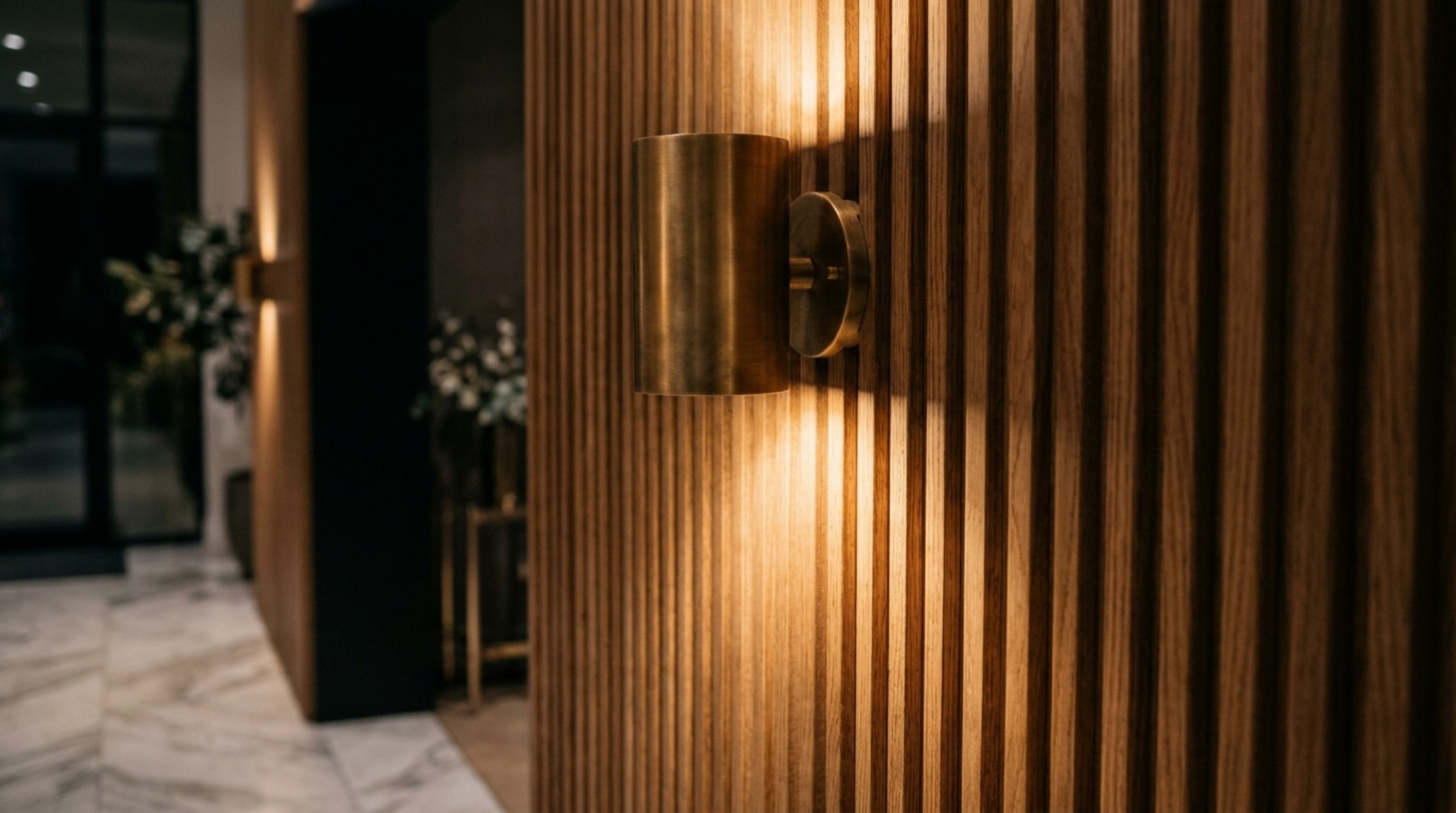 Close-up of 2700K warm-dim lighting casting soft shadows on a textured limewash wall in a luxury designer foyer. Close-up of 2700K warm-dim lighting casting soft shadows on a textured limewash wall in a luxury designer foyer.