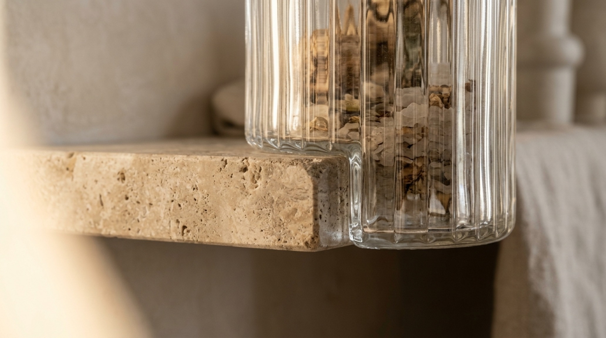 Close-up of honed travertine shelf risers showing natural texture and porous stone details in a bespoke pantry design.