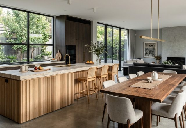 integrated kitchen living dining layout featuring a minimalist waterfall island and a transition to a sunken living room with fluted oak wall paneling
