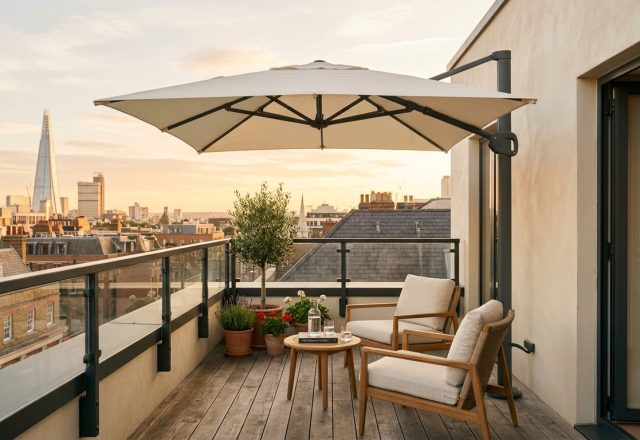 A serene urban balcony sanctuary featuring Benjamin Moore Swiss Coffee walls and a high-end cantilevered umbrella from the Best Patio Umbrellas Review.