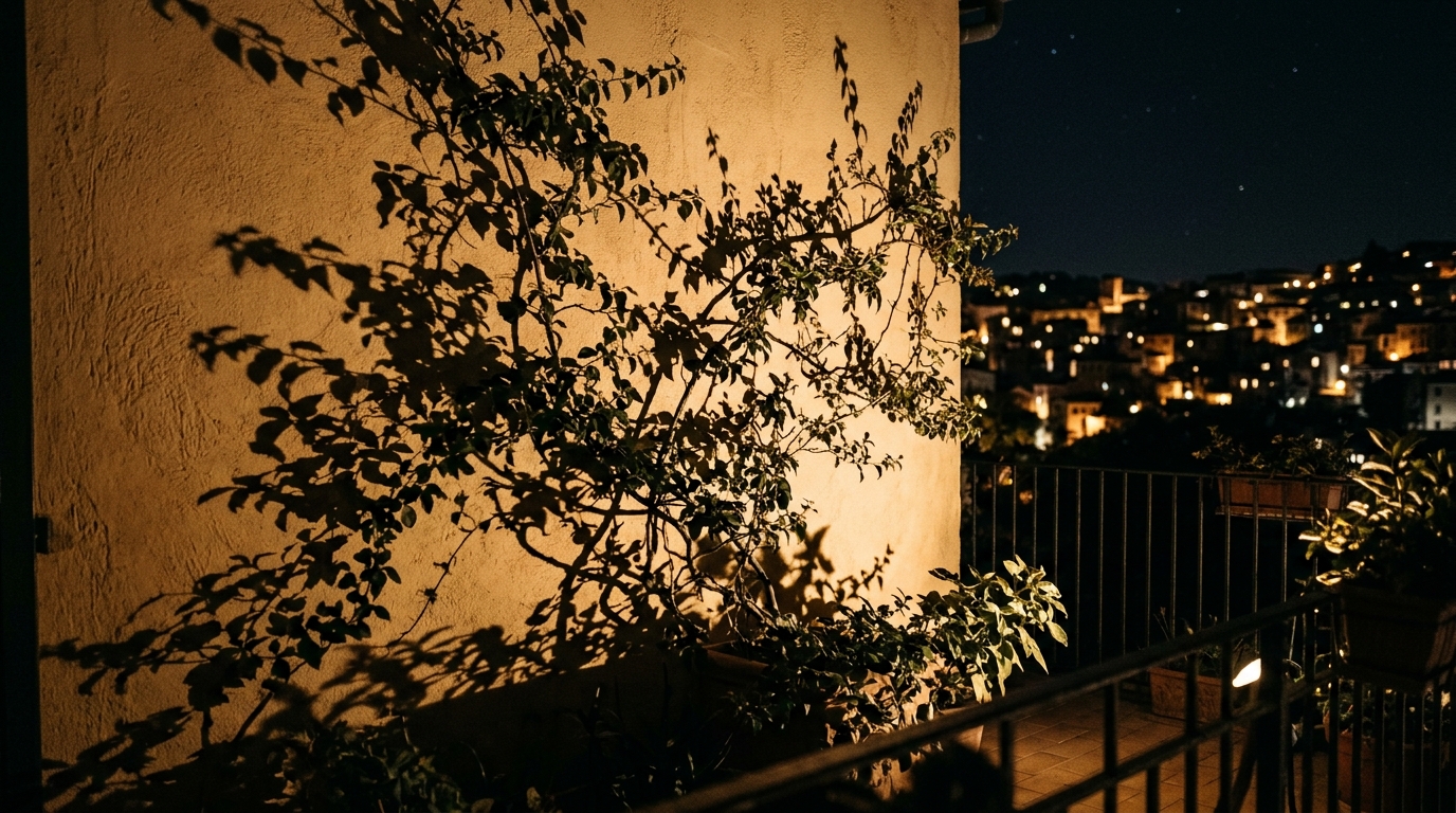 Shadow play on a balcony wall created by a spotlighted Bundt pan planter and trailing vines at 2700K.