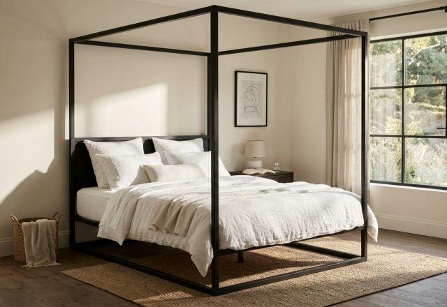 Minimalist black iron canopy bed frame in a master suite with white Belgian linen bedding and warm 2700K architectural lighting, demonstrating core canopy bed decor ideas.