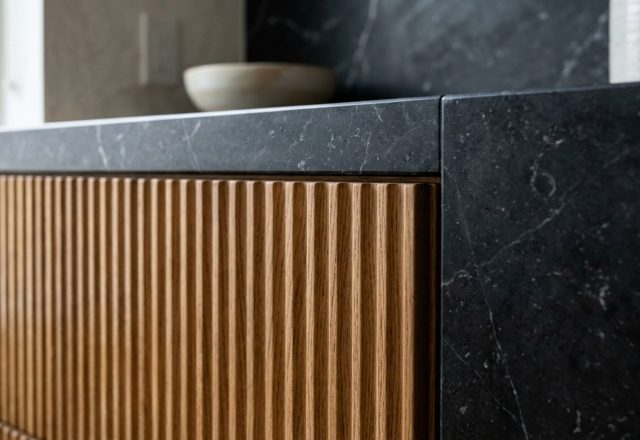 luxury contemporary kitchen furniture textures featuring fluted white oak cabinetry paired with a honed Nero Marquina marble countertop and integrated shadow gap detailing