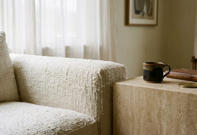 luxury inexpensive apartment decorating ideas textures featuring a close-up of a heavy Belgian linen sofa layered with a chunky waffle-weave throw and a honed travertine side table.