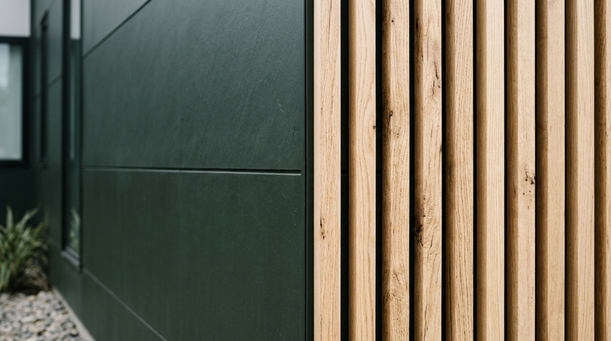 Architectural detail of dark matte vinyl siding adjacent to a floor-to-ceiling glass window, reflecting the surrounding forest and creating a sense of negative space. Architectural detail of dark matte vinyl siding adjacent to a floor-to-ceiling glass window, reflecting the surrounding forest and creating a sense of negative space.