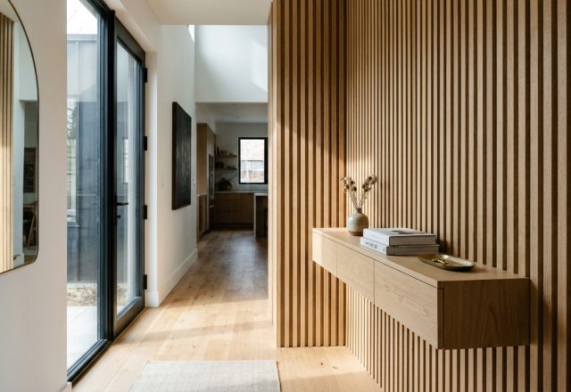 A narrow entryway featuring a floating white oak console and vertical wood slats, showcasing modern narrow entryway ideas with 36-inch clearance.